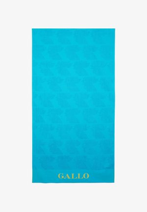 Asciugamano da spiaggia turchese con un motivo ripetuto di silhouette, con un logo dorato "GALLO" sul bordo inferiore. Tessuto morbido e testurizzato.