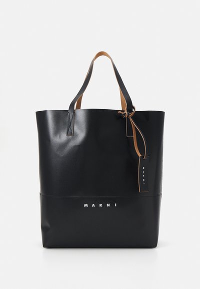 Borsa tote nera realizzata in materiale testurizzato, con manici in pelle marrone chiaro e un logo bianco sulla parte anteriore. Sicura con un dettaglio legato.