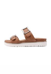 Sandal in suede color tan con due ampie cinghie dotate di fibbie quadrate in argento, poggianti su una suola piatta bianca con battistrada testurizzato.