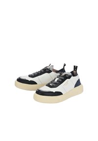 Sneakers bianchi e neri con suola in gomma texturizzata, lacci grigi e dettagli blu navy. Presentano un logo sul lato. Materiali lisci e resistenti.