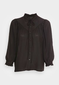 Blouse noire avec un col haut à volants, manches longues bouffantes et boutons sur le devant. Tissu doux et texturé avec une finition légèrement brillante.