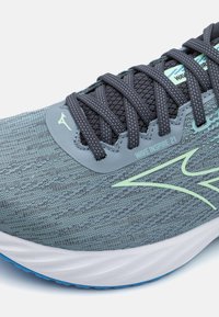 Chaussure de course avec un dessus en maille gris clair, des lacets gris foncé, des accents vert menthe et une semelle intermédiaire blanche dotée d'une semelle extérieure texturée bleue.