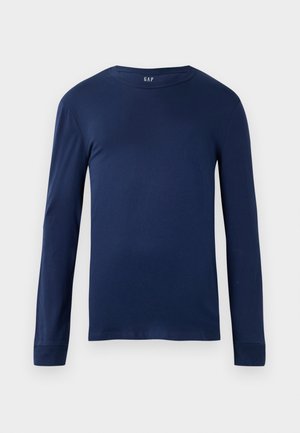 Sötétkék, hosszú ujjú póló puha pamutszövetből, kerek nyakkivágással és illeszkedő ujjakkal. Minimalista dizájn jellemzi, minták nélkül.