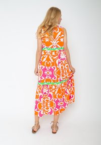 Maxikleid mit einem orangenen, pinken und weißen Blumenmuster, einem grünen Akzent an der Taille und einem fließenden Saum. Weiche Stofftextur.
