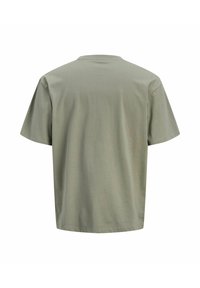 Oliwkowa koszulka z krótkim rękawem z miękkiego materiału, z klasycznym okrągłym dekoltem i luźnym, swobodnym krojem, z jednolitą tylną częścią.