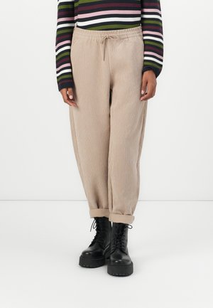 Beige corduroy pants with a relaxed fit, featuring an elastic waistband and rolled cuffs, paired with black lace-up boots.