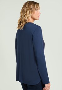 Marineblauw long-sleeve top met een afgeronde zoom, zachte textuur en een relaxte pasvorm, met een eenvoudig ontwerp en zonder zichtbare patronen of accenten.
