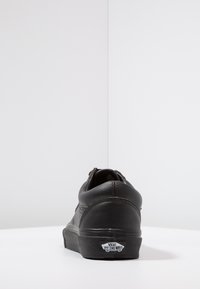 Sneaker in pelle nera con punta arrotondata, superficie texture e suola in gomma nera. Presenta il logo Vans sul tallone.