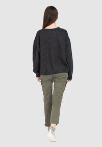 Tmavě šedý oversized svetr s texturovaným úpletem a žebrovaným lemem, spárovaný s olivově zelenými cargo kalhotami s bočními kapsami a úzkým střihem.