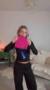 Ματζέντα σκούφος με ετικέτα κρατιέται ψηλά· δομημένη, πλεκτή υφή· εμφανίζεται μπροστά σε απαλό εσωτερικό φόντο με λευκό καναπέ.