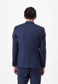 Marineblauer maßgeschneiderter Anzug aus glattem Material, mit einem einzelnen Schlitz hinten und kontrastierenden Knöpfen an den Manschetten.