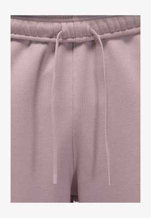 Primer plano de la cintura de unos pantalones deportivos malva con cordones a juego que cuelgan sueltos sobre una textura de tela.