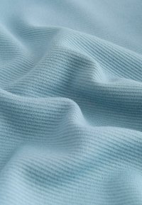 Hellblaues Baumwollgewebe mit einem strukturierten, gerippten Muster. Das Material wirkt weich und hat eine glatte, leicht glänzende Oberfläche.