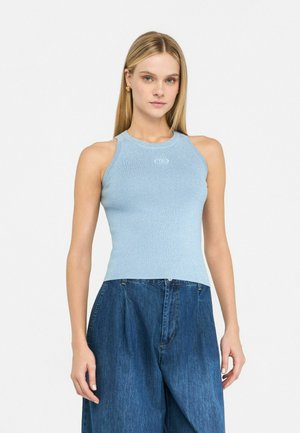 Canotta azzurro chiaro a costine con scollatura rotonda e un leggero luccichio, con un piccolo logo sul petto, abbinata a jeans blu a gamba larga.