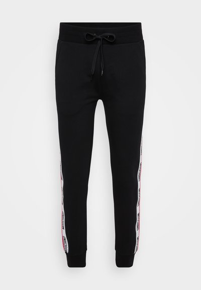 Črne trenirke z elastičnim pasom in vrvico, z rdečimi in belimi bočnimi črtami z napisom. Narejene iz mešanice mehke bombažne tkanine.