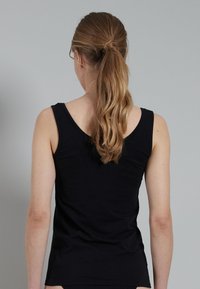 Zwarte tanktop met een aansluitend ontwerp, ronde halslijn en brede schouderbanden. Gemaakt van zachte stof met een gladde textuur.