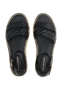 Mustat espadrille-sandaalit, joissa on punottuja hihnoja, litteä pohja ja kudottu juteereuna. Sisältää logon pohjassa ja sivusolkiyksityiskohdan.