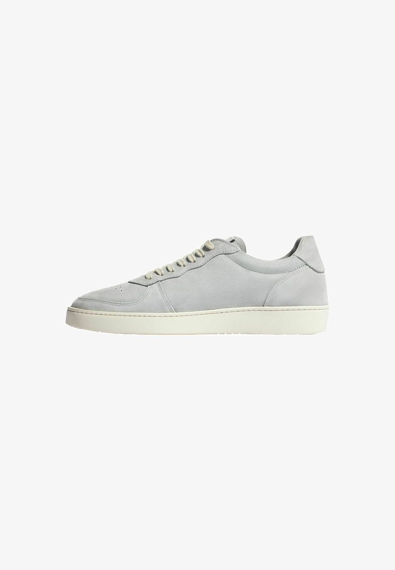 Grå suede sneakers med rund tå, flad hvid gummisål og matchende snørebånd. Har minimal syning og perforeringer nær tåen.