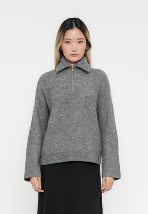 Maglione grigio con zip e colletto alto, realizzato in un morbido tessuto texturizzato. Presenta maniche lunghe e una vestibilità rilassata.