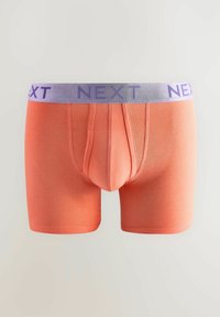 Narancssárga boxer alsónadrág elasztikus anyagból, világoslila gumipánttal, amelyen nagybetűs "NEXT" felirat található.