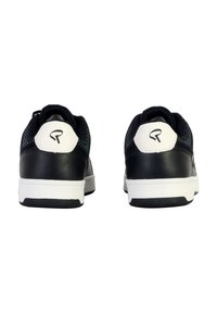 Zapatillas negras con parte superior de cuero sintético, suela de goma blanca y acentos en el talón que contrastan. Presenta un logotipo estilizado en el talón.