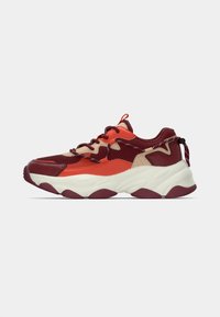 Multicolored sneaker featuring a mesh upper in red and beige tones, thick white sole with maroon accents, and contrasting laces.