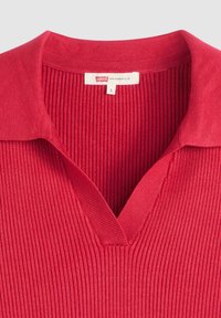 Röd ribbad stickad pikétröja med V-ringning, etikett med varumärket "Levi's" och storlek "S" inuti kragen.