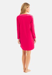 Langärmliges Kleid aus leuchtend pinkem Stoff mit weißen Paspelierungen entlang der Schultern, entspannter Passform und knielangem Schnitt.