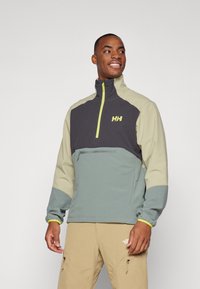 Fleece-Pullover in Grau, Beige und Grün, mit hohem Kragen, Reißverschluss-Taschen vorne und Logo auf der Brust. Strukturierter Stoff.