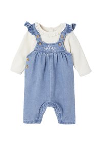 Blaue Denim-Latzhose mit Holzknöpfen, besticktem Blumenmuster auf dem Latz und einem weißen Langarmoberteil mit Rüschenausschnitt.