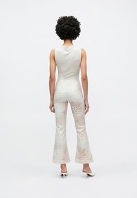 Ανοιχτό γκρι ολόσωμη φόρμα χωρίς μανίκια με φαρδιά πόδια, με διακριτικό μοτίβο ζώου σε μπεζ, κατασκευασμένη από μαλακό, ελαστικό ύφασμα.