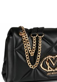 Czarna pikowana torebka skórzana z złotymi łańcuchami i dużym złotym logo "Love Moschino" z przodu.