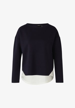 Schwarzes Langarmshirt mit Boots-Ausschnitt und weißem, mehrlagigem Saumdetail, das vorne und hinten übersteht.