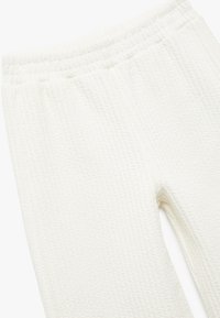 Witte textuurbroek met een geweven patroon, voorzien van een elastische tailleband en een ontspannen pasvorm. De stof lijkt zacht en lichtgewicht.