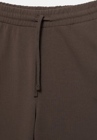 Brązowe spodnie dresowe o miękkiej, gładkiej fakturze i elastycznym pasie. Wyposażone w sznurek do regulacji. Prosty, jednolity design.
