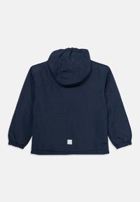 Mörkblå huva jacka med elastiska ärmslut, en bakficka och en fyrkantig logotypdetalj i nedre delen av ryggen. Tillverkad av ett mjukt, lätt material.