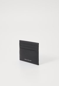 Black leather cardholder with smooth texture, four card slots, and white stitching. Features embossed text "NATURAL FULL GRAIN LEATHER."