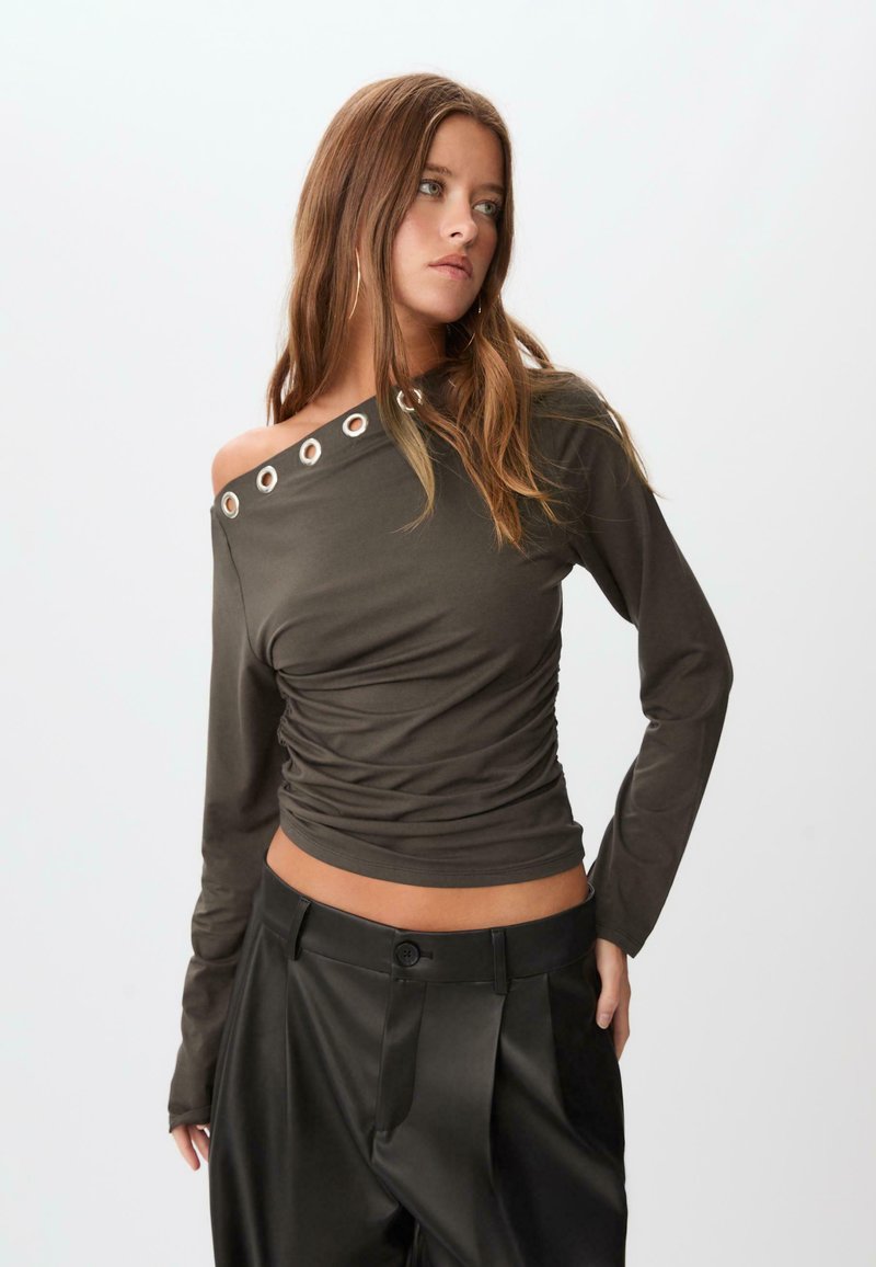 Mørke olivengrøn langærmet skjorte med en rynket design og off-the-shoulder stil, der har sølvfarvede øjer detaljer ved halsudskæringen.