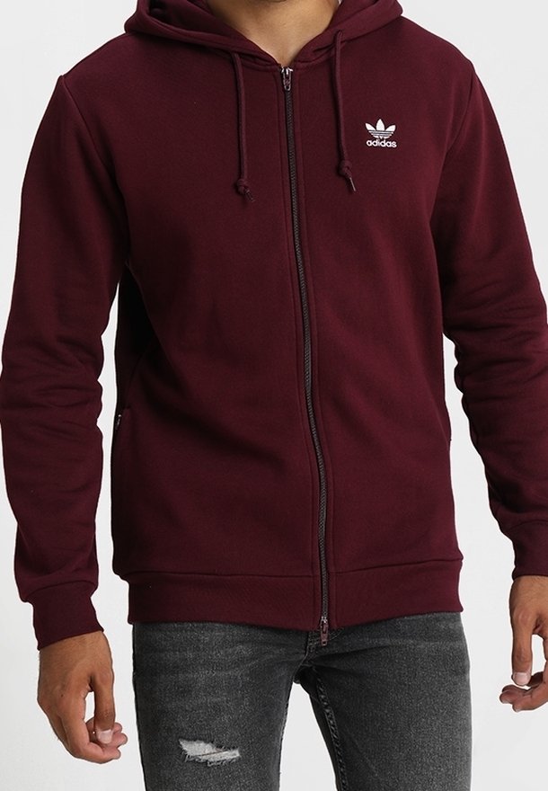 Sudadera con cremallera burdeos en mezcla de algodón, con capucha ajustable y logo de Adidas en blanco en el lado izquierdo del pecho. Puños y dobladillo acanalados.