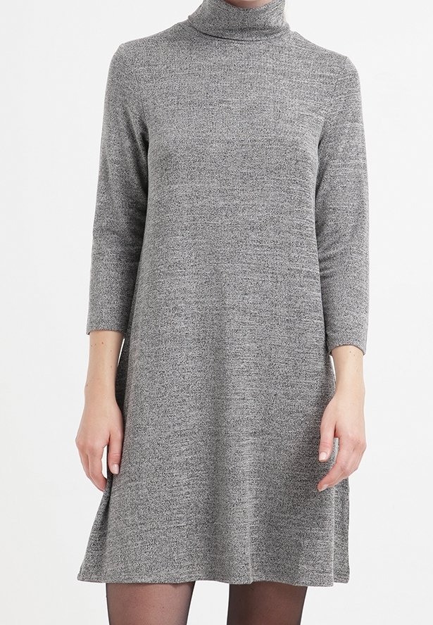 Robe grise en maille à col roulé avec manches trois-quarts, portée par une personne se tenant devant un fond blanc uni.