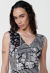 Rochie fără mâneci cu un model alb-negru, având un decolteu în V, motive paisley și florale intricate, și texturi cu dungi mixte.