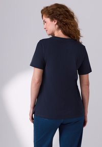 Tumesinine lühikeste varrukatega T-särk ümaralt kaelusega ja sirge lõikega. Pehme tekstuur, minimalistlik disain ning külgedel lõhikud ääres.