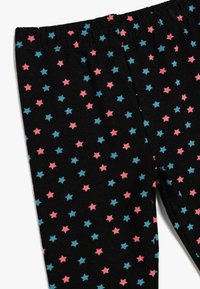 Zwarte leggings met een elastische tailleband, voorzien van een patroon van afwisselend roze en blauwe sterren over de stof.