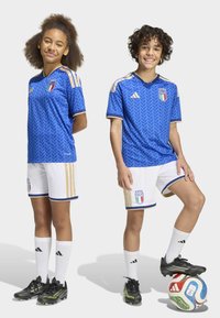 Blue soccer jersey with herringbone pattern, gold accents, and Italy crest. White shorts with gold stripes; players wear black cleats and white socks.