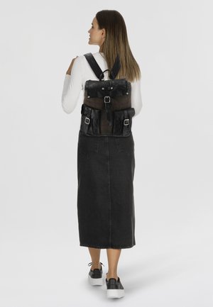 Sac à dos en cuir noir avec une section en tissu imprimé, des bretelles réglables, plusieurs poches et des accents en métal argenté.