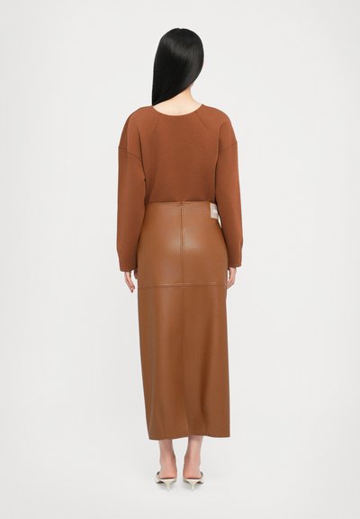 Rjav dolg rokav s krožnim izrezom, v kombinaciji z oprijetim rjavim maxi krilom iz umetnega usnja, ki ima šive in zadnji etiket.