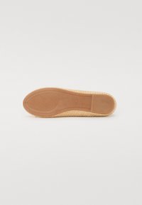 Semelle de chaussure tressée beige avec une finition lisse et un motif de grip texturé. Bout arrondi et bords surélevés le long des côtés. Matériau en caoutchouc souple.