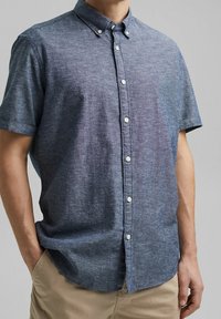 Korte mouwen knoopshirt in donkerblauwe textuurstof met een subtiel patroon en witte knopen, met een klassieke kraag en een relaxed fit.