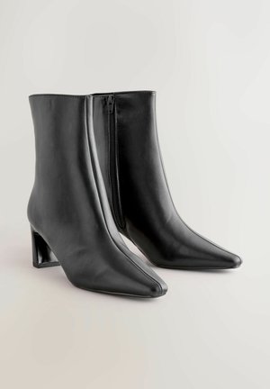 Sorte læder ankelstøvler med spids tå og blokhæl. Har en sidelukning for nem påtagning og en glat overflade.