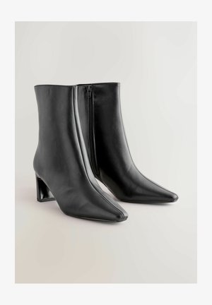 Mustat nahka nilkkurit, joissa on terävä kärki ja paksu korko. Varusteena sivuvetoketju helppoa pukemista varten ja sileä pinta.